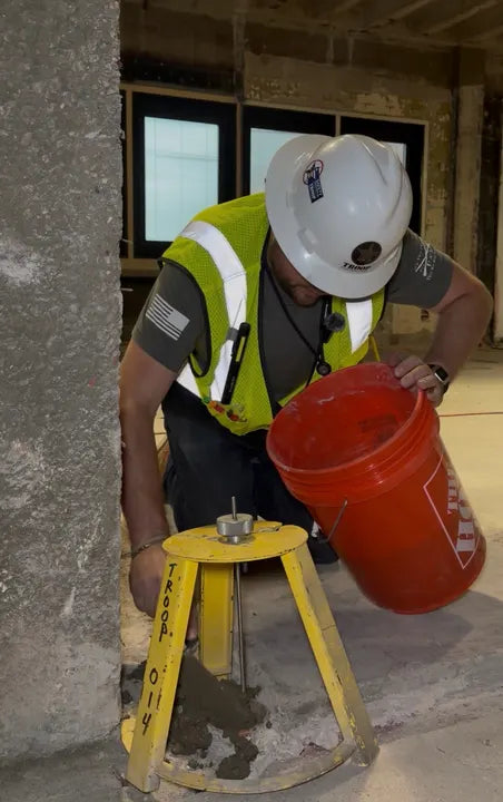 Troop Contracting crew member filling a core hole with a HoleMole Stand in place